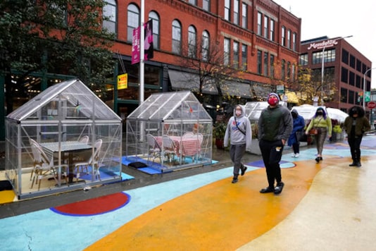 FILE - In this Oct. 18, 2020, file photo, people walk by outdoor plastic dining bubbles on Fulton Market in Chicago. The United States is approaching a record for the number of new daily coronavirus cases in the latest ominous sign about the disease's grip on the nation. (AP Photo/Nam Y. Huh, File) FILE - In this Oct. 18, 2020, file photo, people walk by outdoor plastic dining bubbles on Fulton Market in Chicago. The United States is approaching a record for the number of new daily coronavirus cases in the latest ominous sign about the disease's grip on the nation. (AP Photo/Nam Y. Huh, File)