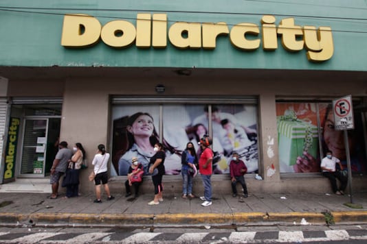 Shoppers, wearing protective face masks, form a line outside Dollarcity in San Salvador, El Salvador, Thursday, Aug. 6, 2020, amid the new coronavirus pandemic. For months, the strictest measures confronting the COVID-19 pandemic in Latin America seemed to keep infections in check in El Salvador, but a gradual reopening combined with a political stalemate has seen infections increase nearly fourfold. (AP Photo/Salvador Melendez)