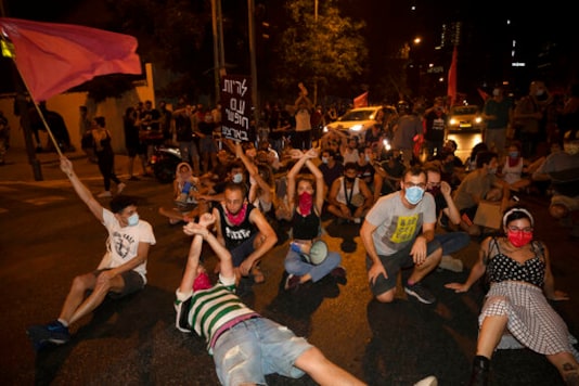 Israeli protesters sit on the street during a demonstration against lockdown measures that they believe are aimed at curbing protests against Prime Minister Benjamin Netanyahu, in Tel Aviv, Israel, Thursday, Oct. 1, 2020. (AP Photo/Sebastian Scheiner) Israeli protesters sit on the street during a demonstration against lockdown measures that they believe are aimed at curbing protests against Prime Minister Benjamin Netanyahu, in Tel Aviv, Israel, Thursday, Oct. 1, 2020. (AP Photo/Sebastian Scheiner)