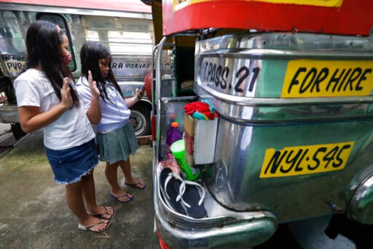 Grade school students Bhea Joy Roxas, right, and Elrich Joy, left, use a smart phone as they raise their hands while reciting the Grade school students Bhea Joy Roxas, right, and Elrich Joy, left, use a smart phone as they raise their hands while reciting the