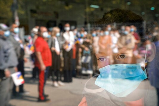 FILE - In this Sept. 19, 2020 file photo, a young girl wearing a mask for protection against COVID-19 infection watches people waiting for the opening of a market selling Romanian food products in Bucharest, Romania. Romania registered on Wednesday, Oct. 7, 2020, the highest levels of COVID-19 infections in 24 hours since the pandemic reached the county in February, with 2958 new cases, the highest number of fatalities, 82 and people in ICU units 612. (AP Photo/Andreea Alexandru, File) FILE - In this Sept. 19, 2020 file photo, a young girl wearing a mask for protection against COVID-19 infection watches people waiting for the opening of a market selling Romanian food products in Bucharest, Romania. Romania registered on Wednesday, Oct. 7, 2020, the highest levels of COVID-19 infections in 24 hours since the pandemic reached the county in February, with 2958 new cases, the highest number of fatalities, 82 and people in ICU units 612. (AP Photo/Andreea Alexandru, File)