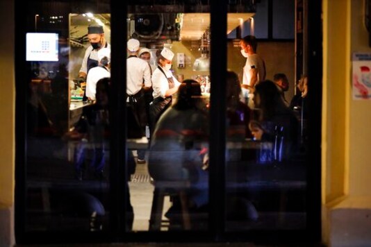 Waiters wearing in face masks and gloves to protect against coronavirus serve customers siting inside a restaurant at Patriarshiye Prudy, a hip restaurant and bar district in Moscow, Russia, late Friday, Oct. 16, 2020. The outbreak in Russia this month is breaking the records set in the spring, when a lockdown to slow the spread was put in place. But, as governments across Europe move to reimpose restrictions to counter rising cases, authorities in Russia are resisting shutting down businesses again. (AP Photo/Alexander Zemlianichenko) Waiters wearing in face masks and gloves to protect against coronavirus serve customers siting inside a restaurant at Patriarshiye Prudy, a hip restaurant and bar district in Moscow, Russia, late Friday, Oct. 16, 2020. The outbreak in Russia this month is breaking the records set in the spring, when a lockdown to slow the spread was put in place. But, as governments across Europe move to reimpose restrictions to counter rising cases, authorities in Russia are resisting shutting down businesses again. (AP Photo/Alexander Zemlianichenko)