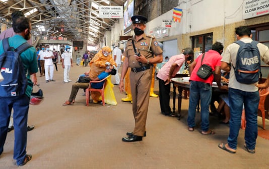 A Sri Lankan police officer stands guard as health officers collect swab samples from rail commuters to test for COVID-19 at a railway station in Colombo, Sri Lanka, Monday, Oct. 12, 2020. (AP Photo/Eranga Jayawardena) A Sri Lankan police officer stands guard as health officers collect swab samples from rail commuters to test for COVID-19 at a railway station in Colombo, Sri Lanka, Monday, Oct. 12, 2020. (AP Photo/Eranga Jayawardena)