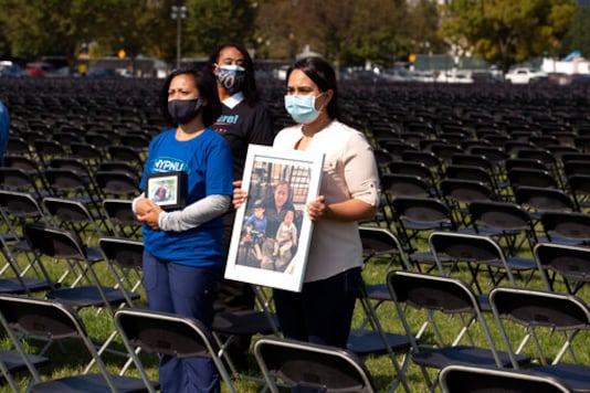 Liza Billing, left, and Naeha Quasba hold photographs of their loved ones, who lost their life due the COVID-19, during the National COVID-19 Remembrance, at The Ellipse outside of the White House, Sunday, Oct. 4, 2020, in Washington. (AP Photo/Jose Luis Magana) Liza Billing, left, and Naeha Quasba hold photographs of their loved ones, who lost their life due the COVID-19, during the National COVID-19 Remembrance, at The Ellipse outside of the White House, Sunday, Oct. 4, 2020, in Washington. (AP Photo/Jose Luis Magana)