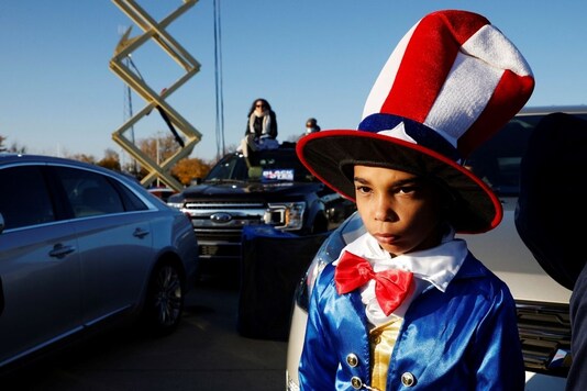 A boy dressed in the colors of the U.S. flag waits for the start of a campaign drive-in, get-out-the-vote event with Democratic U.S. presidential nominee Joe Biden and former U.S. President Barack Obama in Detroit, Michigan, U.S., October 31, 2020. REUTERS/Brian Snyder
