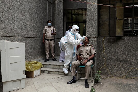 A healthcare worker wearing personal protective equipment (PPE) collects a swab sample from a policeman amidst the spread of the coronavirus disease (COVID-19), at a testing center in New Delhi. REUTERS