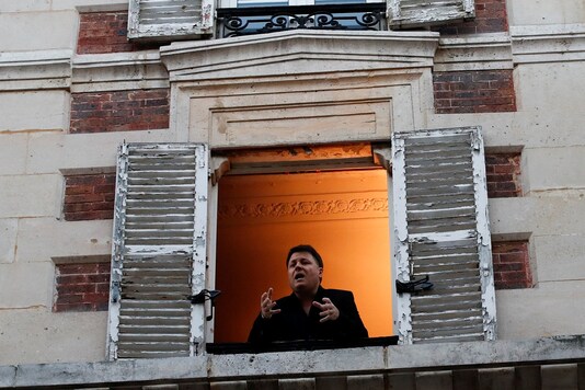 FILE PHOTO: French tenor singer Stephane Senechal sings from his apartment window in Paris as a lockdown is imposed for Covid-19. REUTERS/Gonzalo Fuentes/File Photo