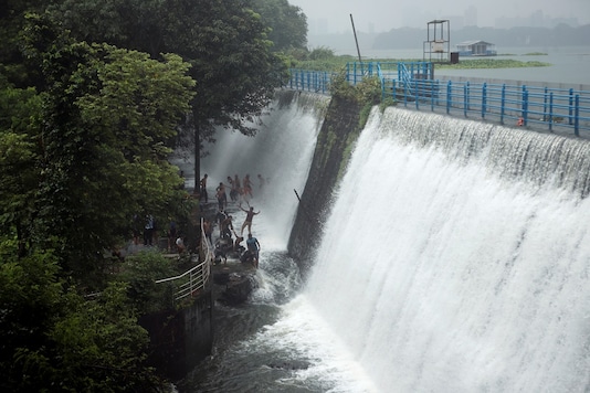 People stand in the water as a lake overflows due to heavy rainfall in Mumbai. (Reuters)