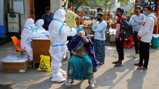 A healthcare worker wearing personal protective equipment (PPE) collects a swab sample from a woman amidst the spread of the coronavirus disease (COVID-19), at Delhi-Uttar Pradesh border, in Noida, India, November 19, 2020. REUTERS/Adnan Abidi
