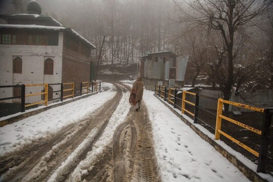 A Kashmir villager wrapped in woolen blanket walks on a snow covered bridge  a day after the season's first snowfall on the outskirts of Srinagar, Indian controlled Kashmir, Tuesday, Nov. 24, 2020. (AP Photo/Mukhtar Khan)