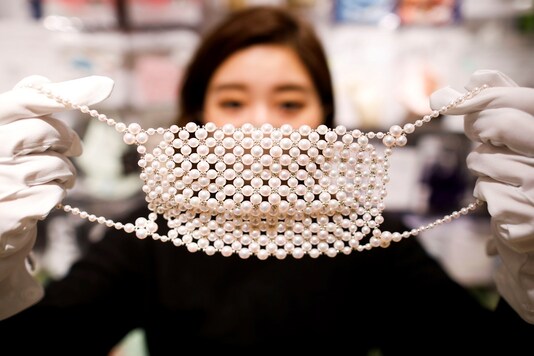 An employee of Cox Co, the operation company of the face-mask speciality shop Mask.com, shows off a luxury face mask made with about 330 pearls which is sellig for one million yen ($9,640).  (Photo: REUTERS/Issei Kato)