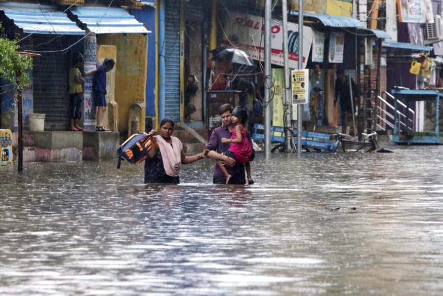  A family wades through a flooded street in Chennai. (Image: AP)