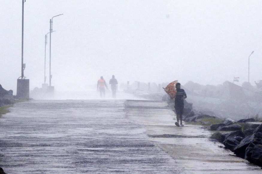  A man tries to hold his umbrella against strong winds at the Kasimedu Harbor on the Bay of Bengal coast in Chennai. (Image: AP)