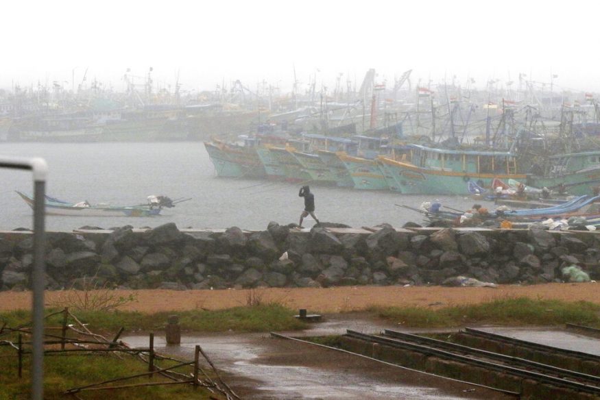  A man walks amid rain at the Kasimedu Harbor on the Bay of Bengal coast in Chennai. (Image: AP)