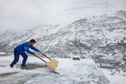 A man clears snow from a roof after fresh snowfall, in Lahaul-Spiti. (PTI)