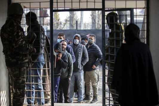 Kashmiris wait in a queue to cast their votes during the first phase of District Development Councils election on the outskirts of Srinagar, (AP Photo/Mukhtar Khan)