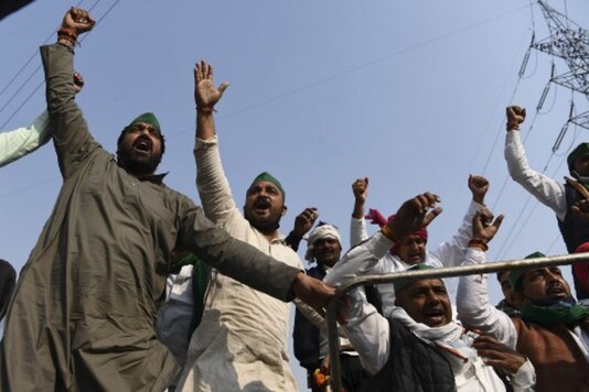 Farmers shout slogans near a police road block at the Delhi-Uttar Pradesh border in Ghazipur on Monday. (AFP)