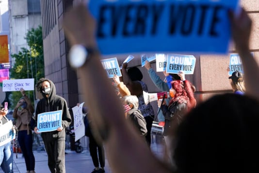 Demonstrators stand across the street from the federal courthouse in Houston, Monday, Nov. 2, 2020, before a hearing in federal court involving drive-thru ballots cast in Harris County. The lawsuit was brought by conservative Texas activists, who have railed against expanded voting access in Harris County, in an effort to invalidate nearly 127,000 votes in Houston because the ballots were cast at drive-thru polling centers established during the pandemic. (AP Photo/David J. Phillip) Demonstrators stand across the street from the federal courthouse in Houston, Monday, Nov. 2, 2020, before a hearing in federal court involving drive-thru ballots cast in Harris County. The lawsuit was brought by conservative Texas activists, who have railed against expanded voting access in Harris County, in an effort to invalidate nearly 127,000 votes in Houston because the ballots were cast at drive-thru polling centers established during the pandemic. (AP Photo/David J. Phillip)
