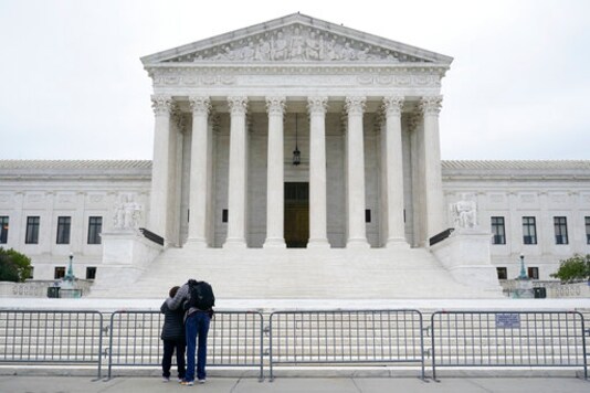 A woman and man pray outside the Supreme Court on Capitol Hill in Washington, Tuesday, Oct. 27, 2020, the day after the Senate confirmed Amy Coney Barrett to become a Supreme Court Justice. (AP Photo/Patrick Semansky)
