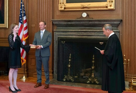 In this image provided by the Collection of the Supreme Court of the United States, Chief Justice John G. Roberts, Jr., right, administers the Judicial Oath to Judge Amy Coney Barrett in the East Conference Room of the Supreme Court Building, Tuesday, Oct. 27, 2020, in Washington as Judge Barrett's husband, Jesse M. Barrett, holds the Bible. (Fred Schilling/Collection of the Supreme Court of the United States via AP)