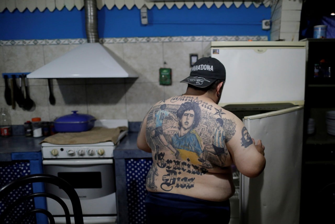 1. Guillermo Rodriguez, a devoted Diego Maradona fan who has images of Maradona tattooed on his back and who owns a pizza shop called Siempre al 10 referring to Maradona's jersey number, opens a refrigerator at his pizza shop in Buenos Aires, Argentina, November 28, 2020. (REUTERS/Ueslei Marcelino)