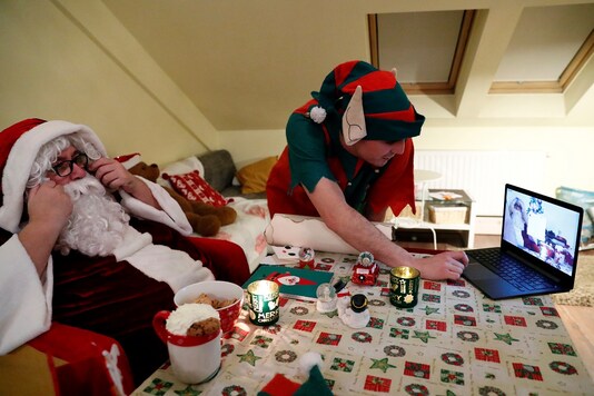 An assistant helps Pal Pillmayer, dressed as Santa Claus, as he prepares to interact with children by video chat in Budapest. (Photo: REUTERS/Bernadett Szabo)