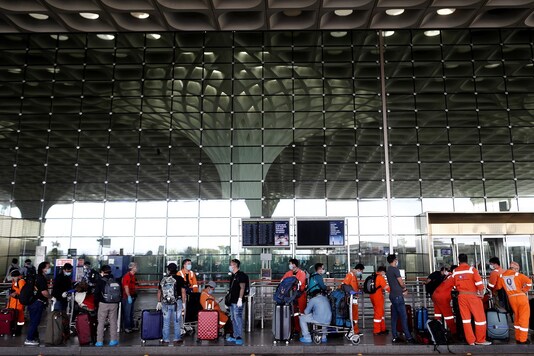 मुंबई में छत्रपति शिवाजी अंतर्राष्ट्रीय हवाई अड्डे में प्रवेश करने के लिए सुरक्षात्मक फेस मास्क पहने यात्री कतार में प्रतीक्षा करते हैं।  (प्रतिनिधि छवि: रायटर)