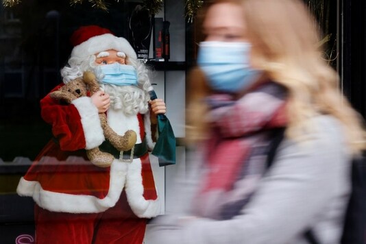 A woman walks past a window display with Father Christmas wearing a protective mask. Photo: Reuters