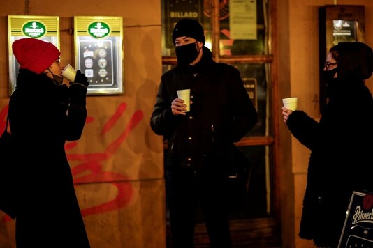 People stand in front of a restaurant drinking mulled wine on the sidewalk as the restaurants and bars have to stay closed due to the current coronavirus disease (COVID-19) rules in Berlin, Germany, December 10, 2020. REUTERS/Hannibal Hanschke