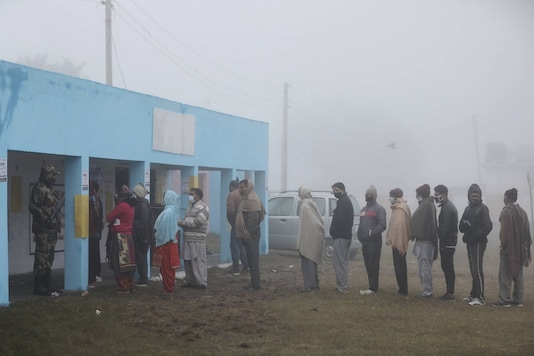 Voters stand in a queue to cast their votes for the sixth phase of District Development Council (DDC) election, at Arnia village in Jammu, Sunday, December 13, 2020. (PTI Photo)