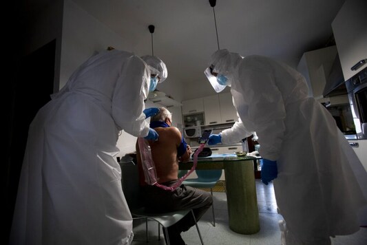 Doctor Luigi Cavanna, left, visits COVID-19 patient Arnaldo Michelotti in his home in Gossolengo, near Piacenza, Italy, Wednesday, Dec. 2, 2020. (AP Photo/Antonio Calanni)