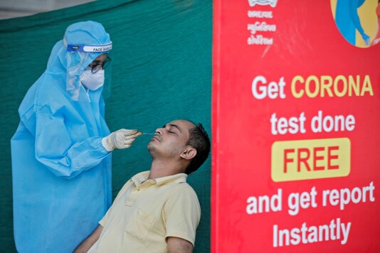 A healthcare worker wearing personal protective equipment (PPE) takes swab from a man during a testing campaign for the coronavirus disease, in Ahmedabad on November 24, 2020. (REUTERS/Amit Dave)