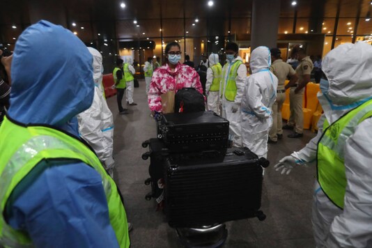 Workers in personal protective equipment guide passengers arriving from United Kingdom on December 22, 2020. (AP Photo/Rafiq Maqbool)
