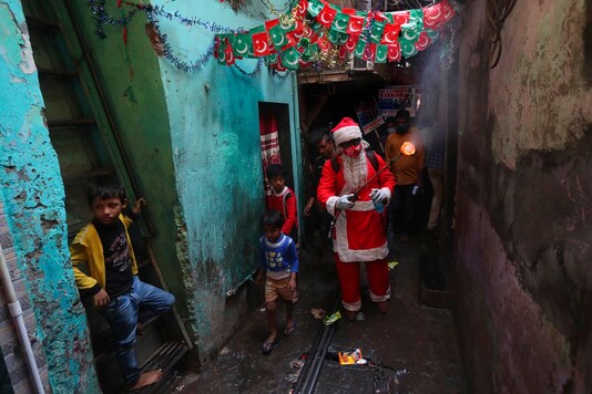 A man dressed as Santa Claus sanitizes a narrow lane in Dharavi, one of Asia's biggest slums, in Mumbai, India, Saturday, Dec. 19, 2020. (Image: AP/Rafiq Maqbool)