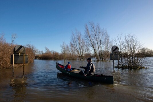 Anthony Gleave and his son Arthur, 3, canoe along the flooded A1101 in Welney, Norfolk, England, Sunday, Dec. 27, 2020. Hurricane-force winds reaching up to 106 miles per hour (170 kph) and rainstorms battered parts of Britain, disrupting train services and stranding drivers in floodwaters. The Isle of Wight saw Storm Bella’s strongest winds at 106mph, while parts of the south coast of England and north Wales also saw gusts of around 80mph (129 kph). (Joe Giddens/PA via AP)