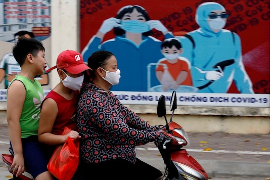 FILE PHOTO: A woman wears a protective mask as she drives past a banner promoting prevention against the coronavirus disease (COVID-19) in Hanoi, Vietnam July 31, 2020. REUTERS/Kham