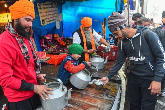 Volunteers serve water and beverages during the ongoing farmer's agitation against new farm laws, at Singhu border in New Delhi, Tuesday, January 12, 2021. (Image: PTI)