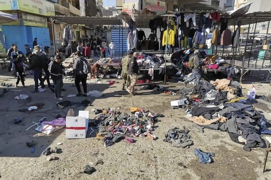 People and security forces gather at the site of a deadly bomb attack in a market selling used clothes, Iraq, Thursday, Jan. 21, 2021. Twin suicide bombings hit Iraq's capital Thursday killing and wounding civilians, police and state TV said. (AP Photo/Hadi Mizban)