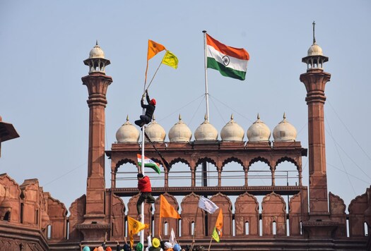 Farmers hoist flags at the Red Fort during the tractor rally on Republic Day. (Image: PTI)