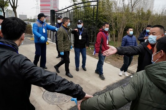 Security personnel clear the way for the convoy of the World Health Organization team as they depart from the Wuhan Jinyintan Hospital after a field visit in Wuhan in central China's Hubei province on Saturday, Jan. 30, 2021