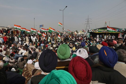 Farmers listen to their leaders during a day-long hunger strike as they continue to protest against three farm laws at the Delhi-Uttar Pradesh border, in New Delhi, India, Saturday, Jan. 30, 2021. Indian farmers and their leaders spearheading more than two months of protests against new agriculture laws began a daylong hunger strike Saturday, directing their fury toward Prime Minister Narendra Modi and his government. Farmer leaders said the hunger strike, which coincides with the death anniversary of Indian independence leader Mahatma Gandhi, would reaffirm the peaceful nature of the protests. (AP Photo/Manish Swarup)