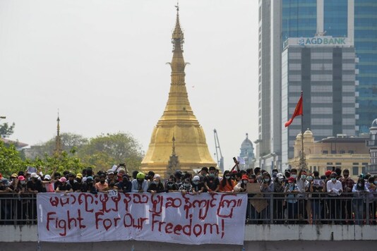 People stand next to a banner during a rally to protest against the military coup and to demand the release of elected leader Aung San Suu Kyi, in Yangon, Myanmar, February 8, 2021. REUTERS/Stringer
