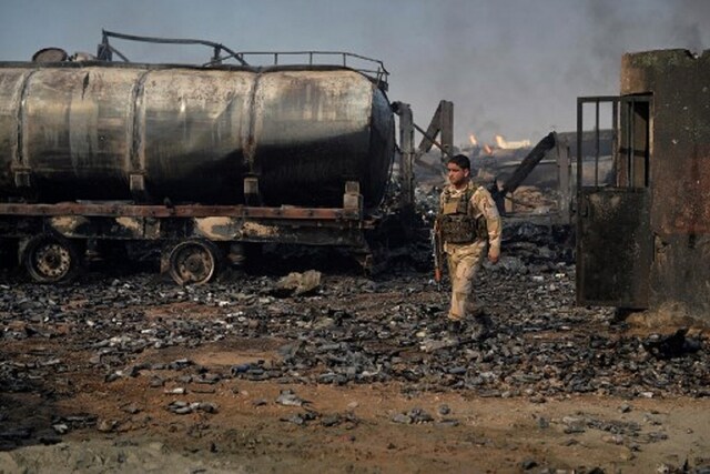 A security forces personnel walks amidst wreckage of gas tankers after a fire accident at Islam Qala on the outskirts of Herat, in the border between Afghanistan and Iran on February 14, 2021. (Image: AFP)