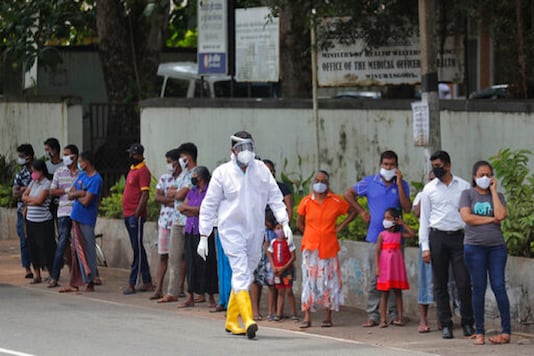 Sri Lankans wait to give swab samples to test for COVID-19 outside a hospital as a health official walks past in Minuwangoda, Sri Lanka. (AP)