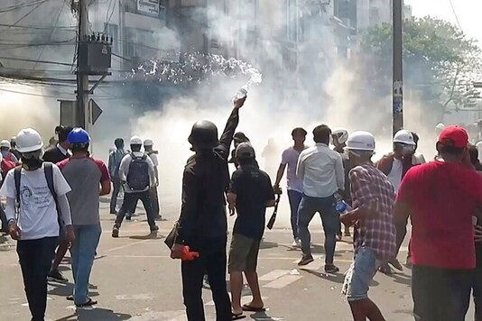 In this image from a video, anti-coup protesters react as smoke from tear gas rises in Yangon, Myanmar on Sunday, February 28, 2021. (AP)