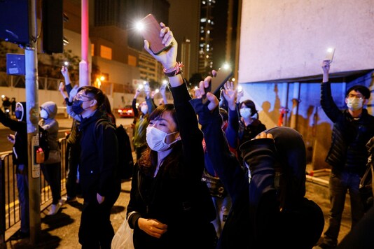 Supporters of pro-democracy activists wave flashlights as a prison van carrying some of 47 activists leaves West Kowloon Magistrates' Courts in Hong Kong. (Reuters)