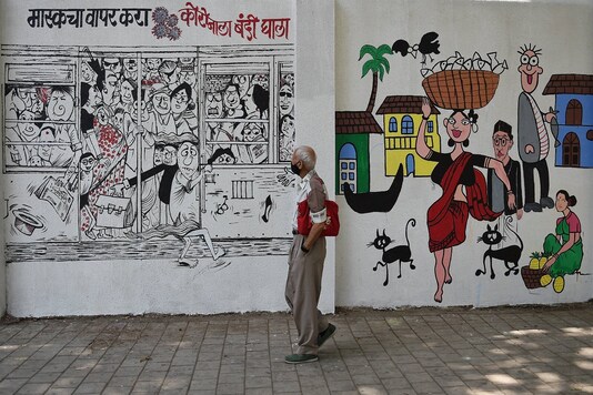 An elderly man wearing a face mask, as a precaution measure against coronavirus, looks at a mural. (PTI)