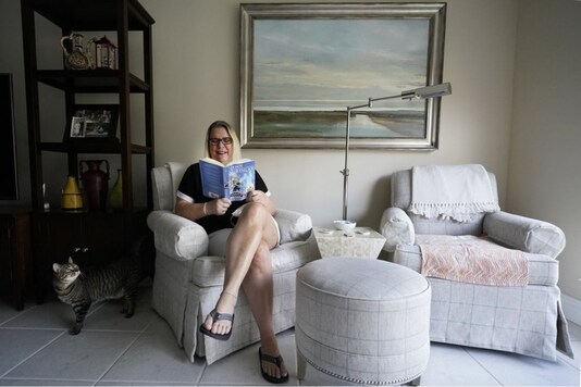 Kelly Vaiman poses for a photo in her living room where she sometimes likes to sit and read, Friday, Feb. 19, 2021, in Boynton Beach, Fla. Vaiman is an avid cozy mystery reader. (AP Photo/Wilfredo Lee)

