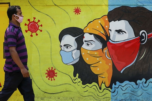 A man wearing a protective mask walks past a graffiti in Navi Mumbai, March 8, 2021. (REUTERS)