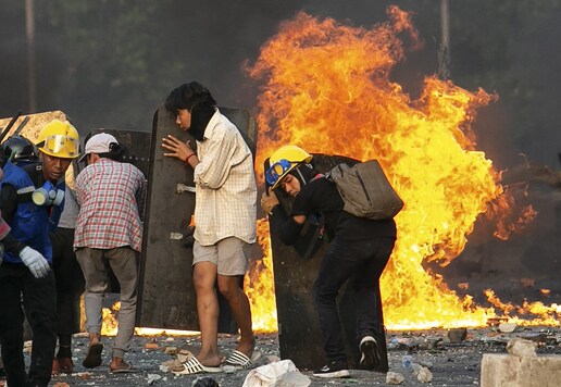 Protesters take cover behind homemade shields as they confront the police during a crackdown on demonstrations against the military coup in Yangon on March 16, 2021. (Photo by STR / AFP)